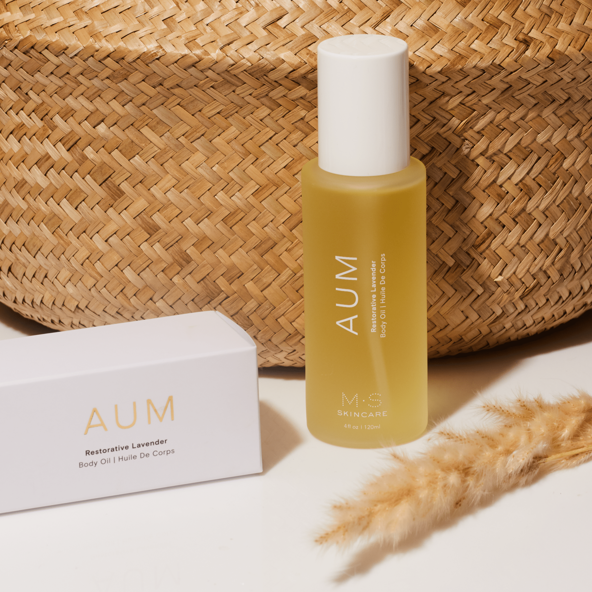 Aum Body Oil in frosted glass bottle in front of straw bottle on msskincare.co