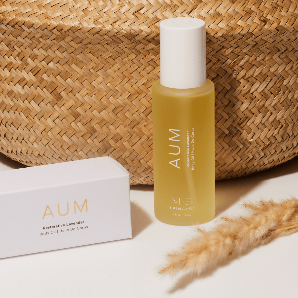Aum Body Oil in frosted glass bottle in front of straw bottle on msskincare.co