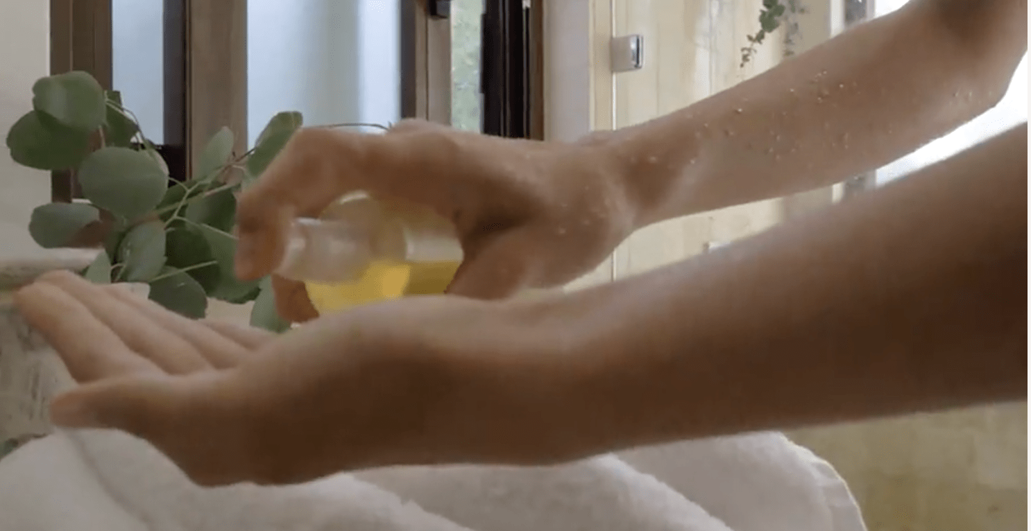 Applying Aum Body Oil by M.S skincare to hands
