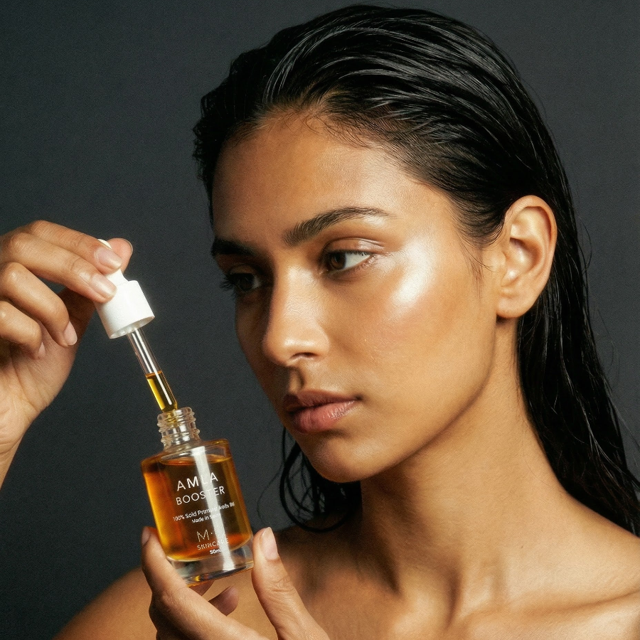 Woman applying Amla oil from glass bottle with white dropper on msskincare.co