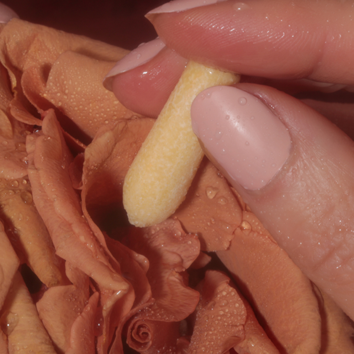 Foria Intimacy Melt held between two fingers, close-up