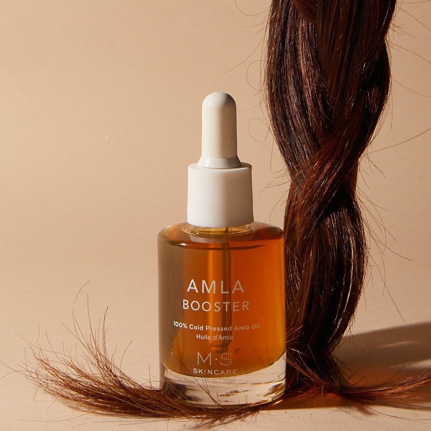 Amla Oil in a glass bottle with a white dropper next to a brown braid on msskincare.co