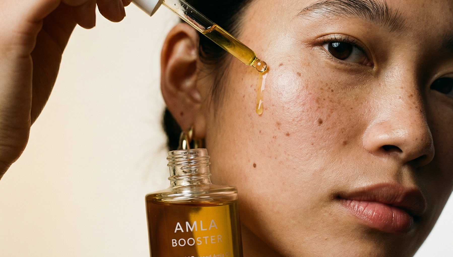 Person applying AMLA Booster serum to their face with a dropper.