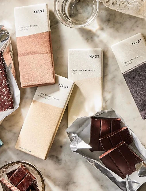 Mast chocolate bars on marble, with squares of dark chocolate on foil