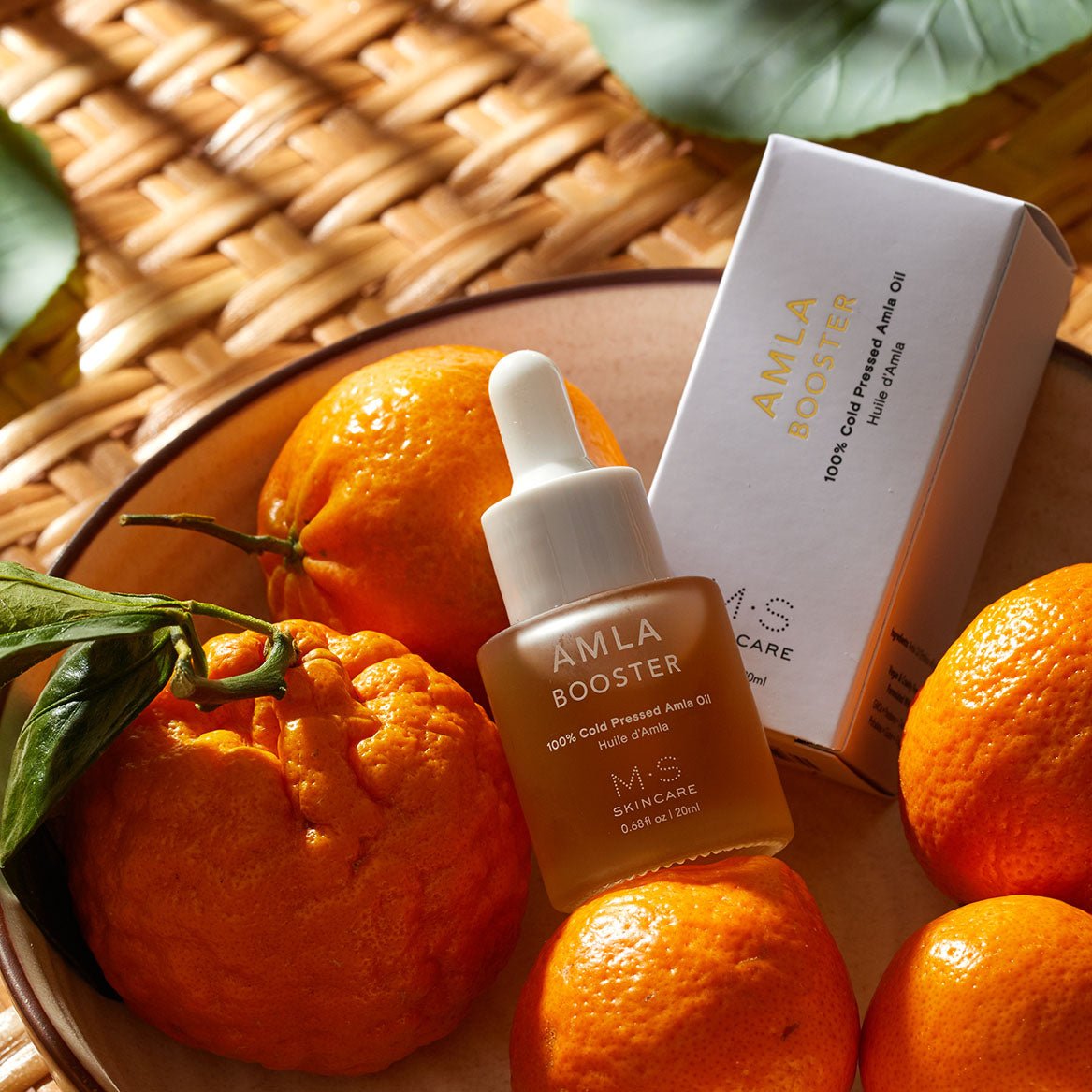 Amla Oil in a frosted white bottle with dropper surrounded by oranges, Ayurvedic vitamin C face and hair oil