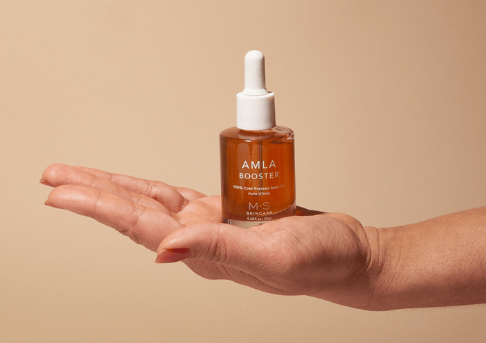 Amla Oil by M.S Skincare in a frosted white bottle with dropper, held in hand