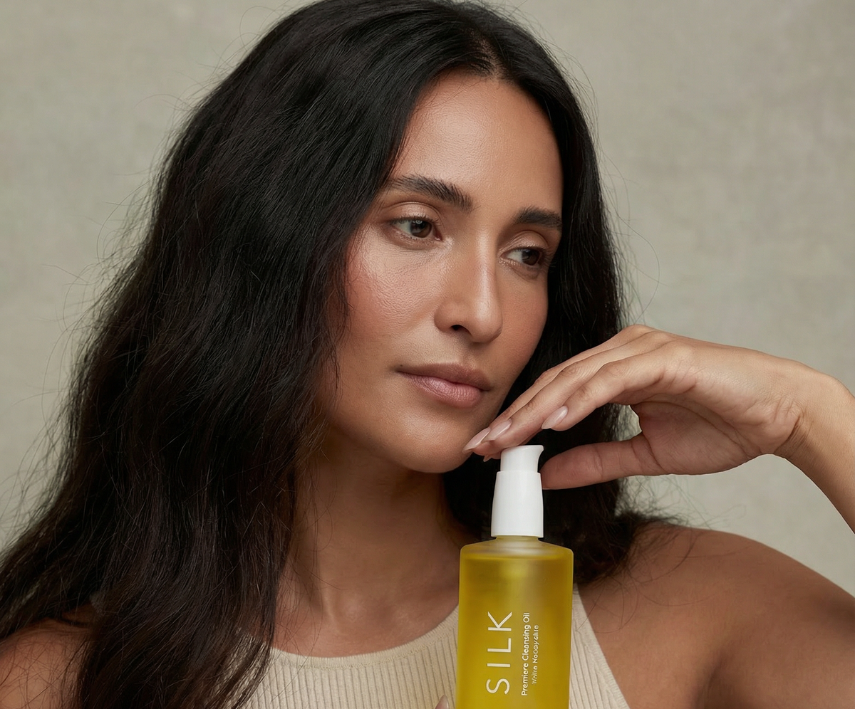 Woman in a cream sweater holding Silk Cleansing Oil